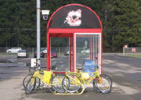 A group of yellow bikes in front of a bus stop on campus